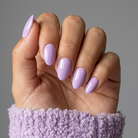 Hand with light purple nail polish on a gray background