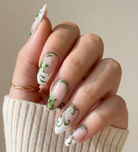 Hand with decorative nail art holding a beige sleeve against a neutral background