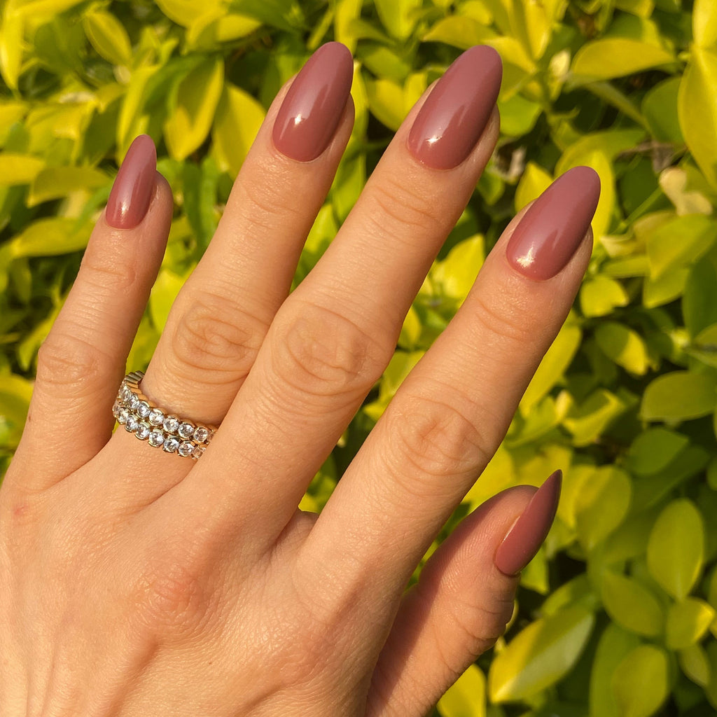 Glossy rose pink press-on nails with an elegant oval shape. A stylish and feminine manicure.